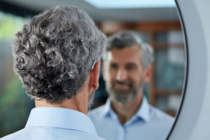 Man wearing hearing aids looking in the mirror