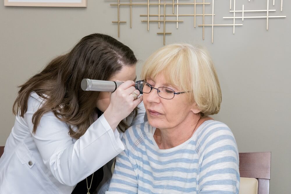 Earwax removal expert inspecting ear of a female patient at Allison Audiology Houston, TX